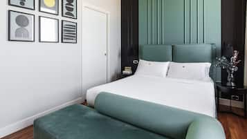 A neatly arranged hotel room with a large bed, a bedside table with a lamp, and a small nightstand.