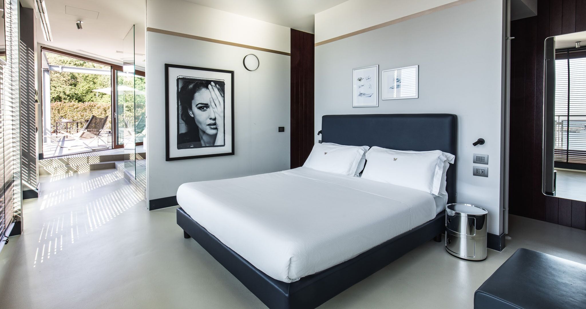 Ein modernes Schlafzimmer mit einem großen Bett, einem Nachttisch und Blick ins Freie.