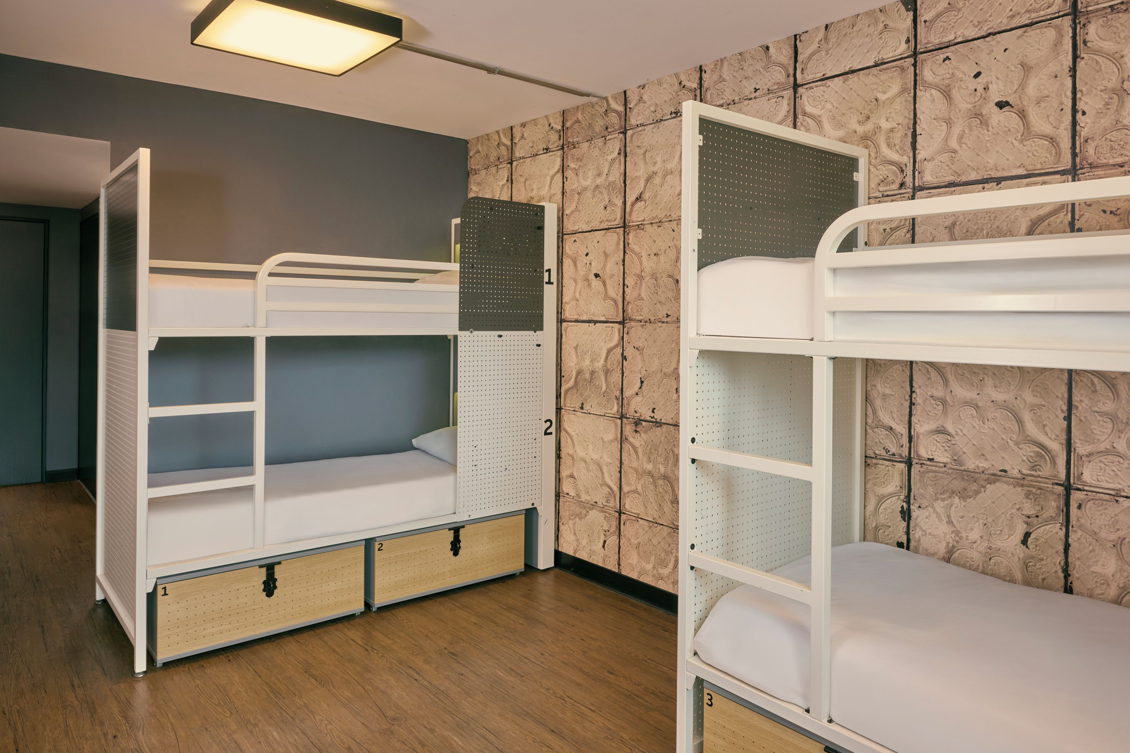 Une chambre avec des lits superposés, un plancher en bois et un mur décoré de motifs.