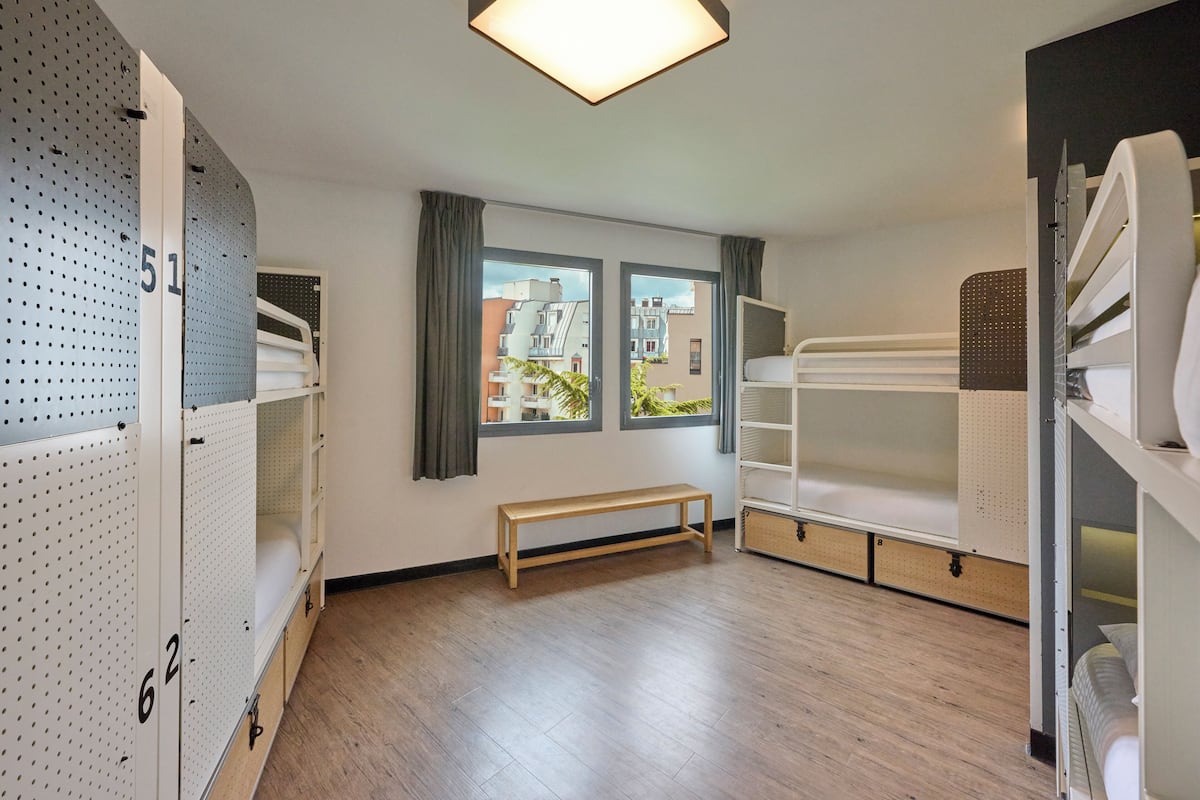Un dormitorio con literas, un banco y unidades de almacenamiento.