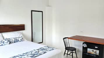 Una camera d'albergo con un letto, una sedia, una scrivania e un frigorifero.