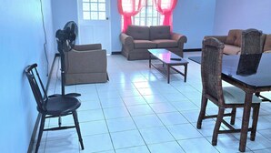 Una sala de estar con un sofá, sillas, una mesa de centro y un televisor montado en la pared.