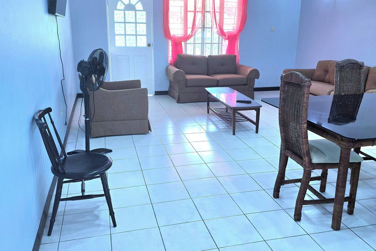 A living room with a sofa, chairs, a coffee table, and a TV mounted on the wall.