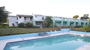Una piscina con sillas de descanso y una valla de madera.