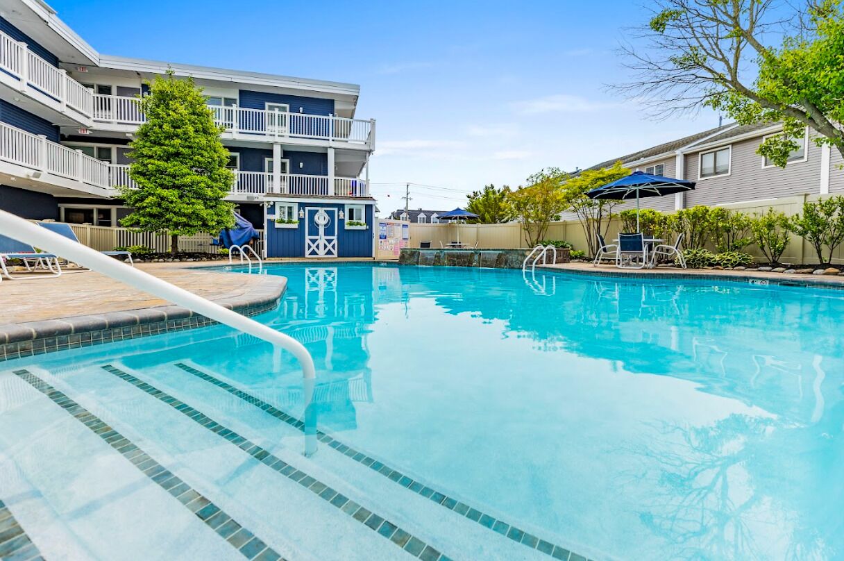 Une piscine à l’eau claire, entourée d’une terrasse en bois et de chaises longues.