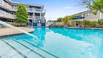 Une piscine à l’eau claire, entourée d’une terrasse en bois et de chaises longues.