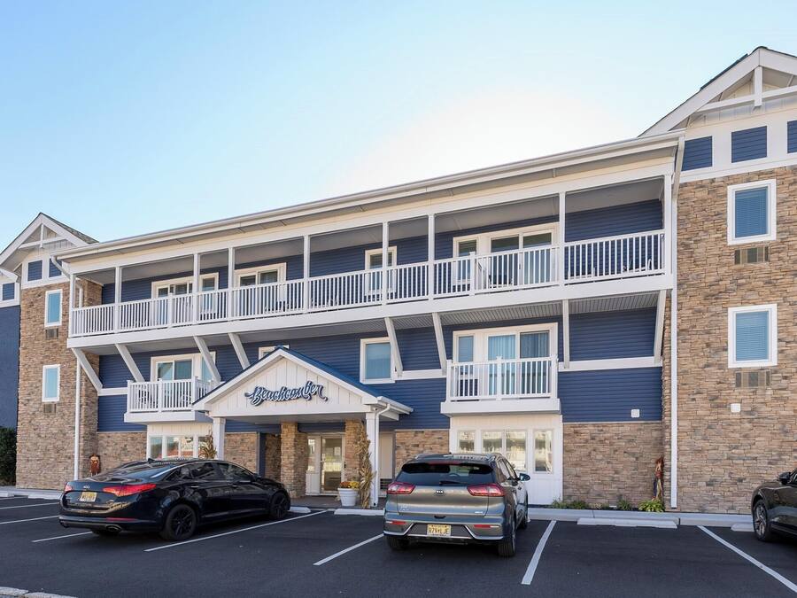A multi-story hotel with a central entrance, balconies, and parking spaces.