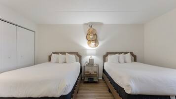 Habitación doble con dos camas, una mesita de noche con lámpara y un perchero en la pared.