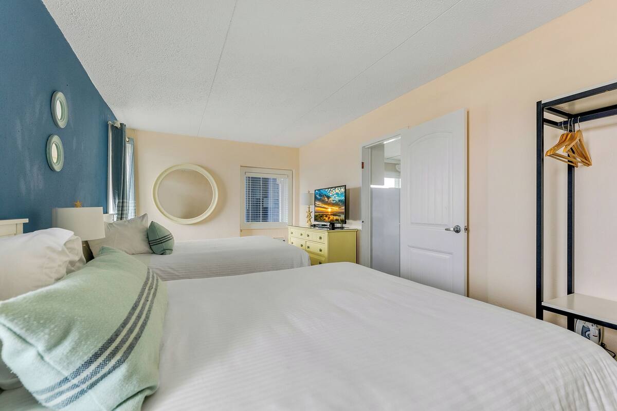A bedroom with two beds, a dresser, a television, and a wardrobe.