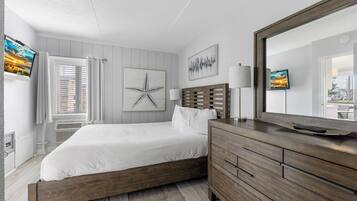 A bedroom with a wooden bed, a dresser, a mirror, and artwork on the walls.