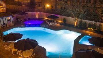 A swimming pool with a built-in slide, surrounded by outdoor seating and umbrellas.