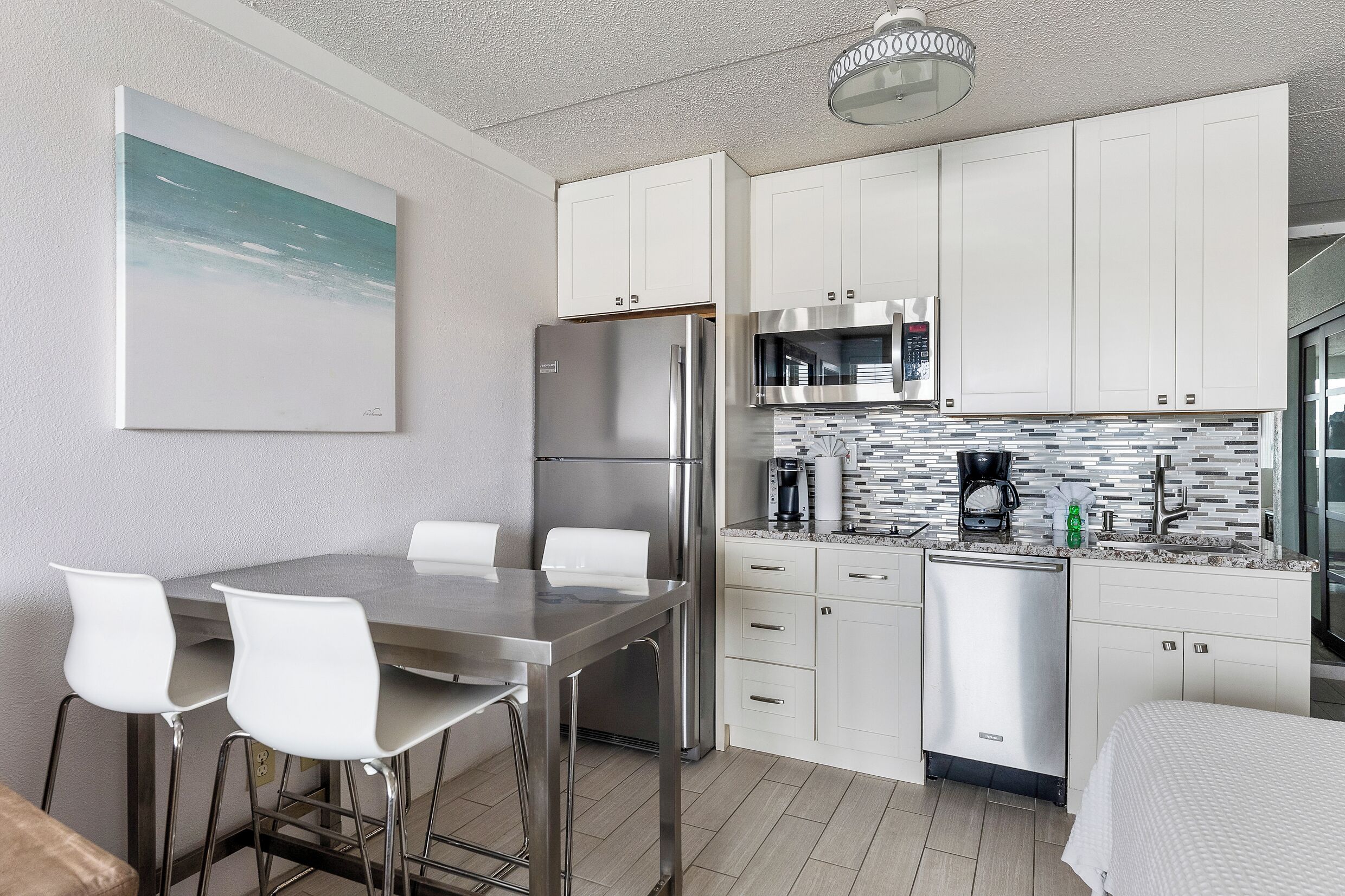 Una cocina moderna con armarios blancos, electrodomésticos de acero inoxidable y salpicadero de azulejos.