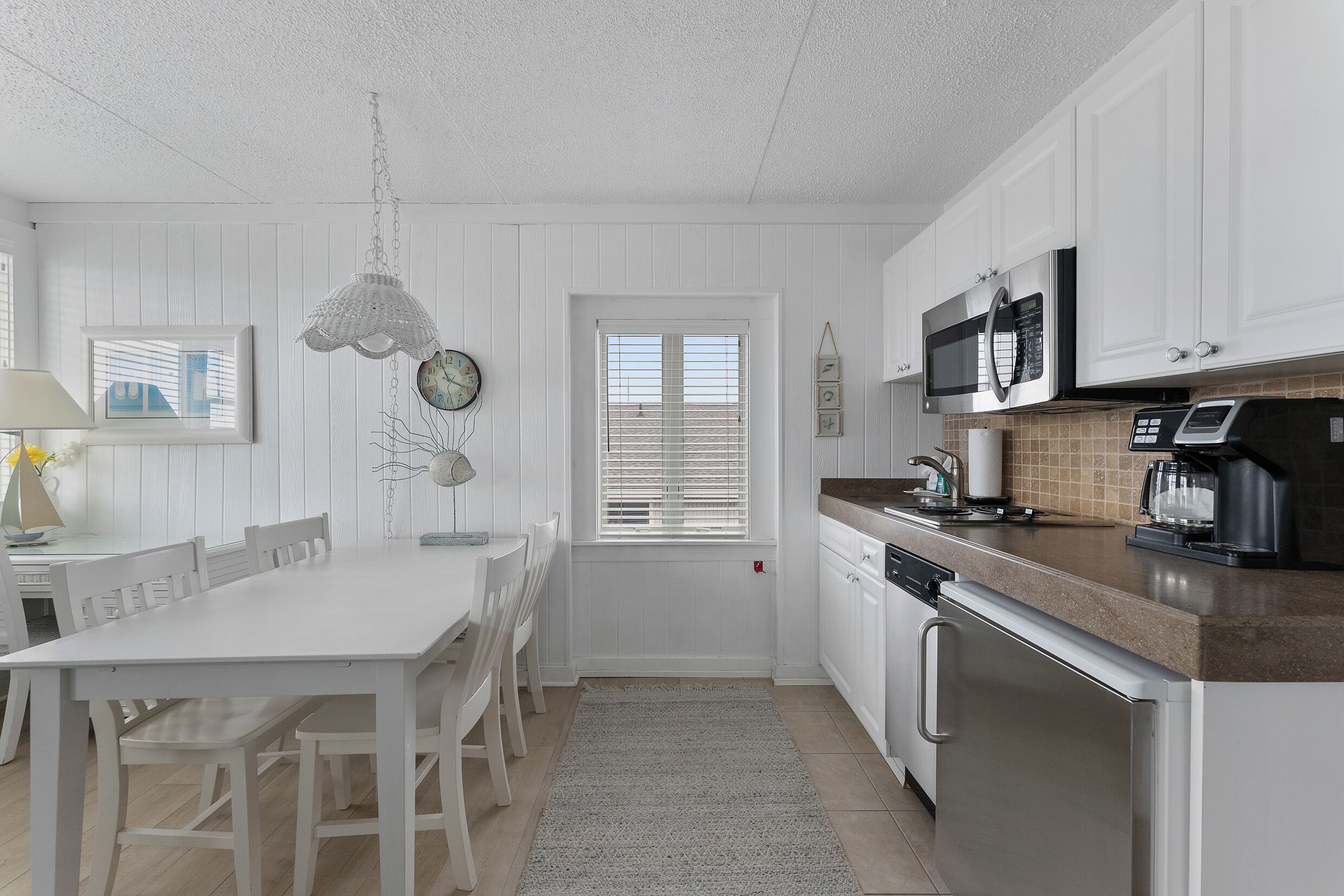A kitchen with white cabinetry, a microwave, a coffee maker, and a dishwasher.