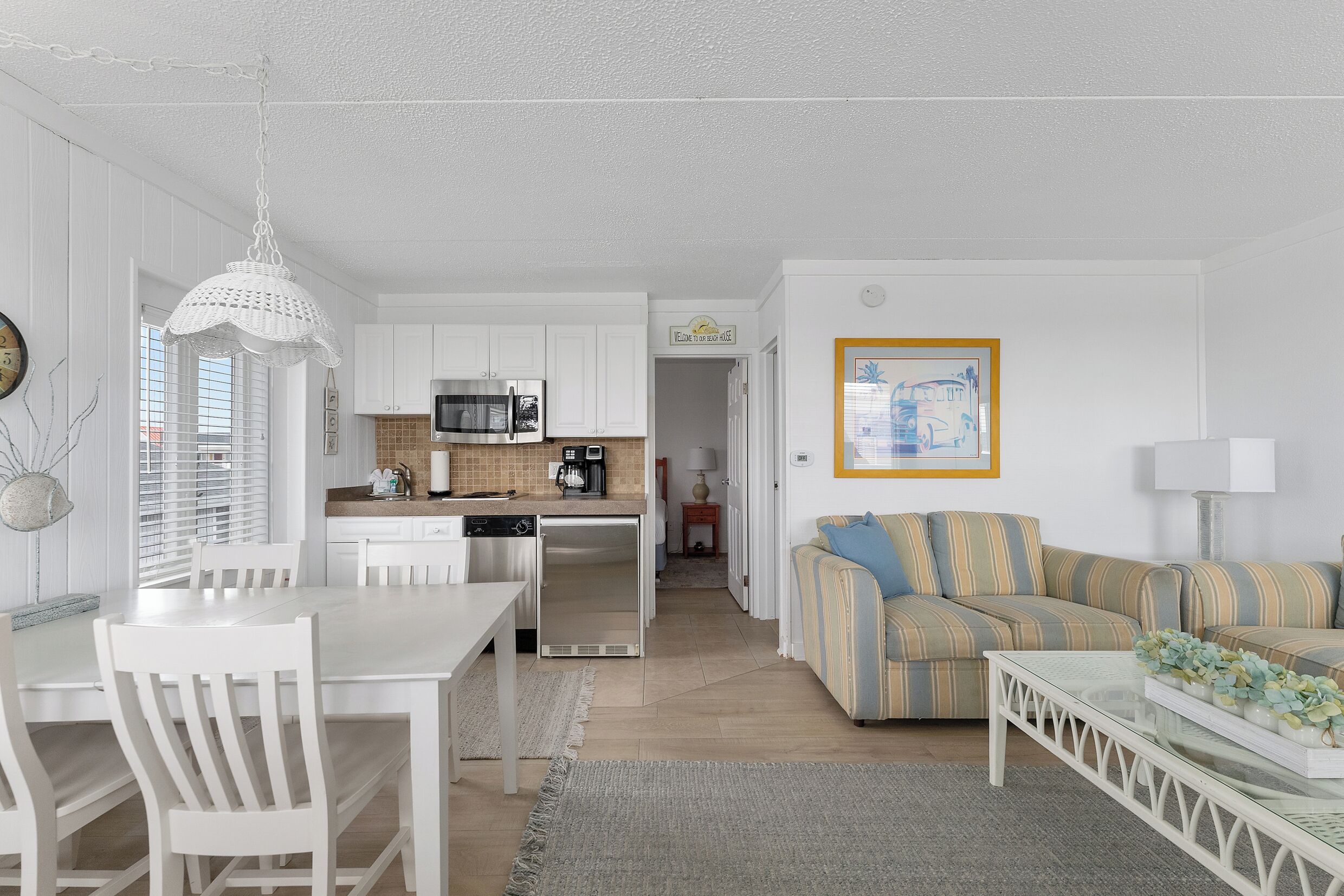 Una sala de estar moderna con una decoración en tonos blancos, un comedor, una cocina y un sofá.
