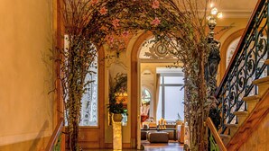 Una imponente escalera con barandales ornamentados, velas y decoración floral que conduce a un comedor.