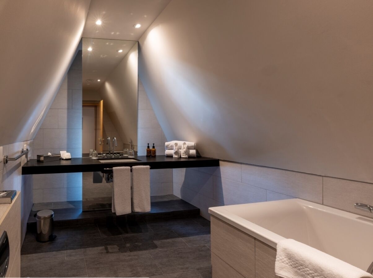 A modern bathroom with a black countertop, white sink, and a large bathtub.