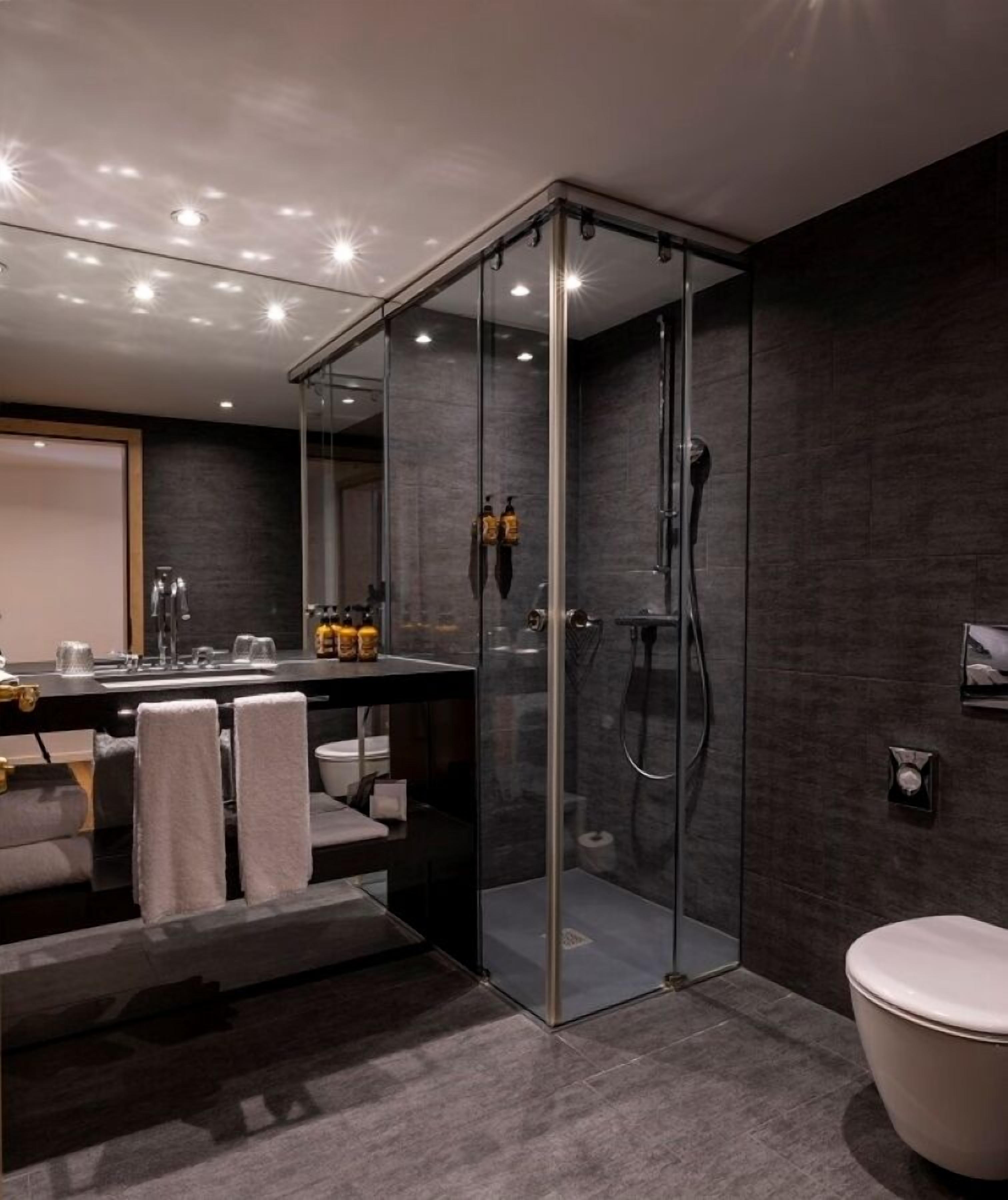A modern bathroom with a glass-enclosed shower, a vanity with a mirror, and a toilet.