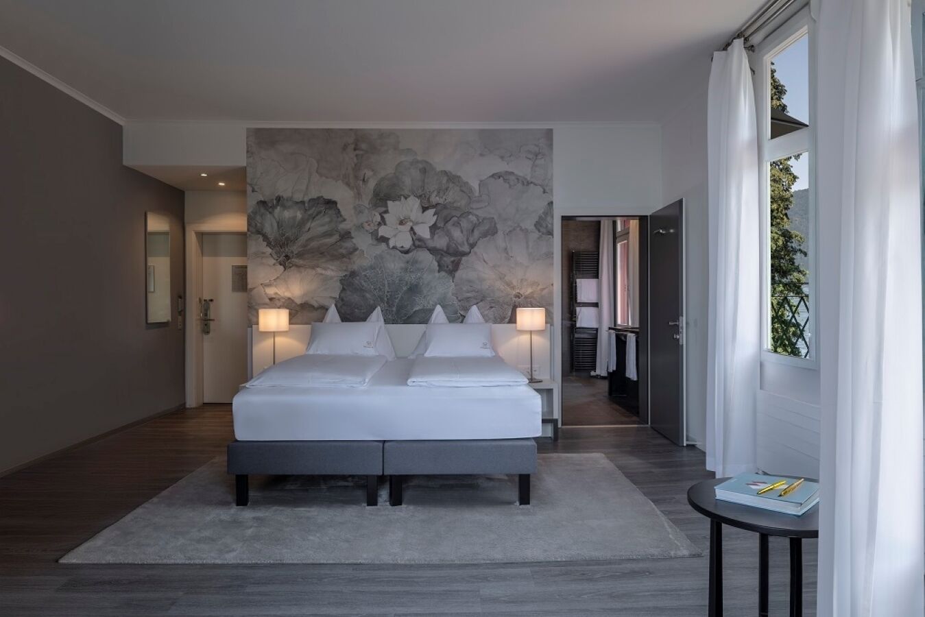 A modern bedroom with a large bed, a stone wall mural, and a view of a balcony.