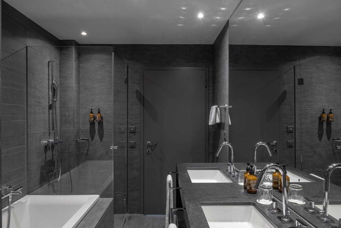 A modern bathroom with two sinks, a shower, and a large mirror.