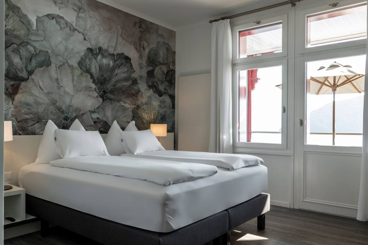 Un dormitorio moderno con una cama grande, un mural en la pared y vistas al exterior a través de amplias ventanas.
