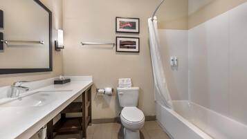 A modern bathroom with a white sink, toilet, and bathtub. There are two framed pictures on the wall and a towel rack.