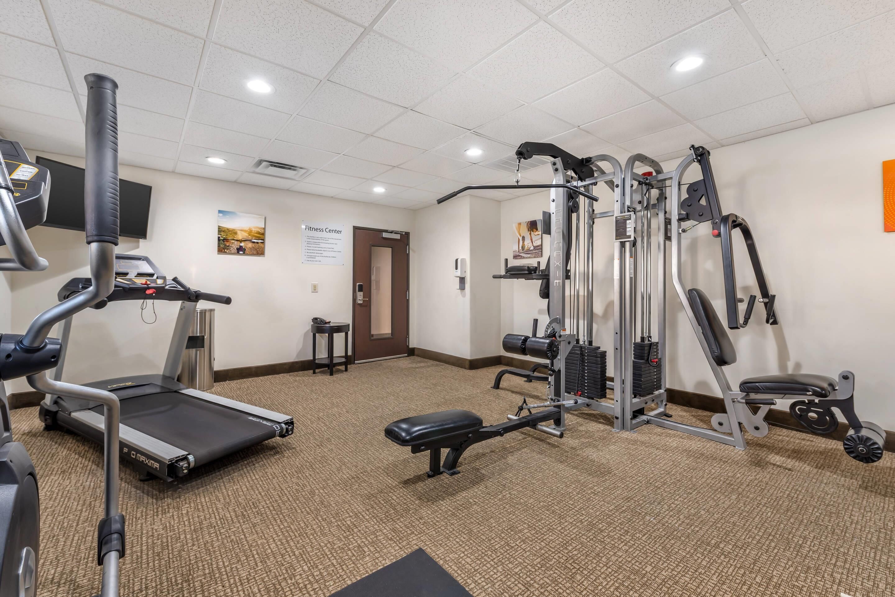 A fitness center with cardio equipment, weight machines, and a bench.