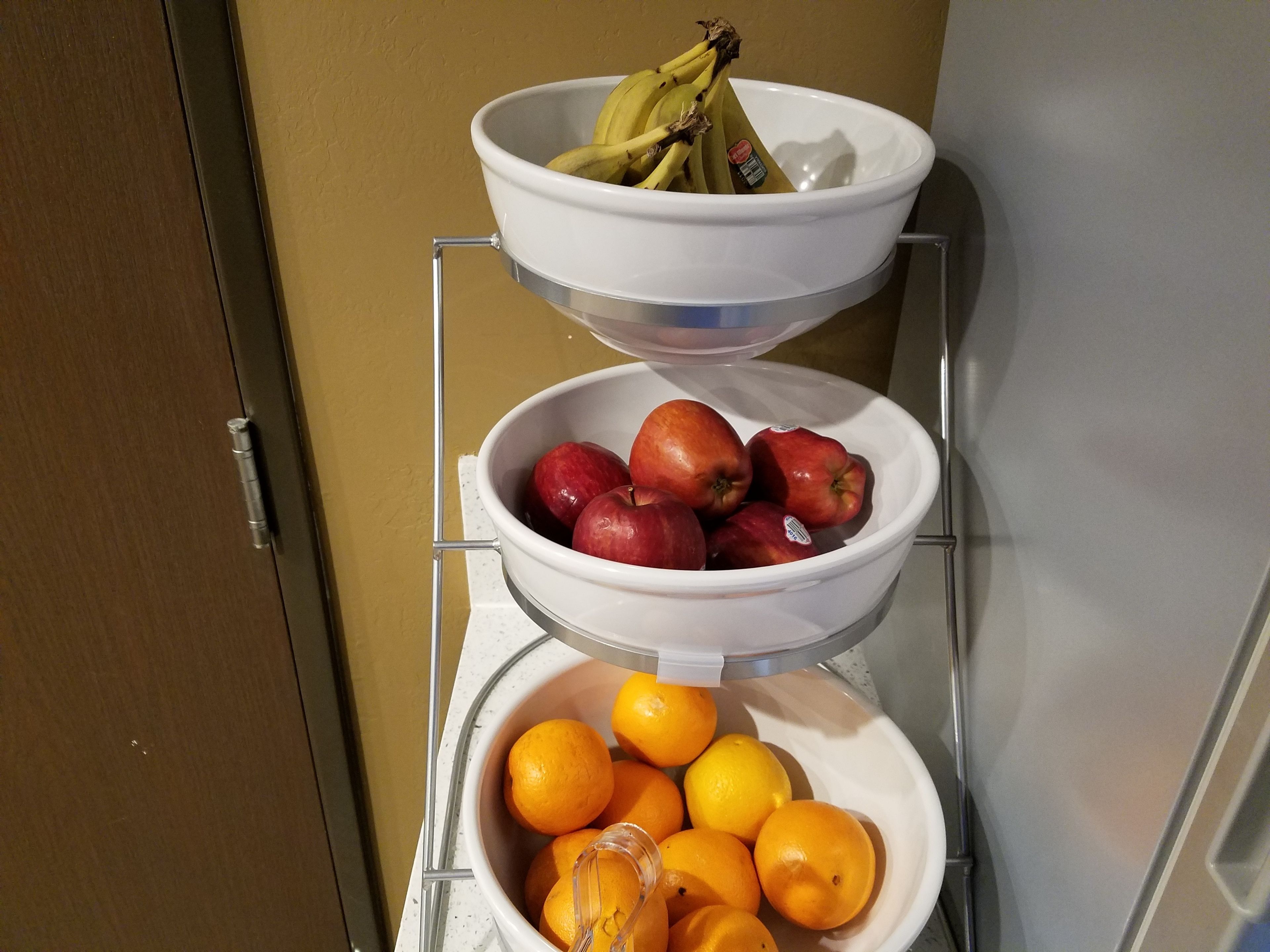 Un réfrigérateur à trois étagères : l’étagère supérieure contient des bananes, l’étagère du milieu contient des pommes et l’étagère inférieure contient des oranges.