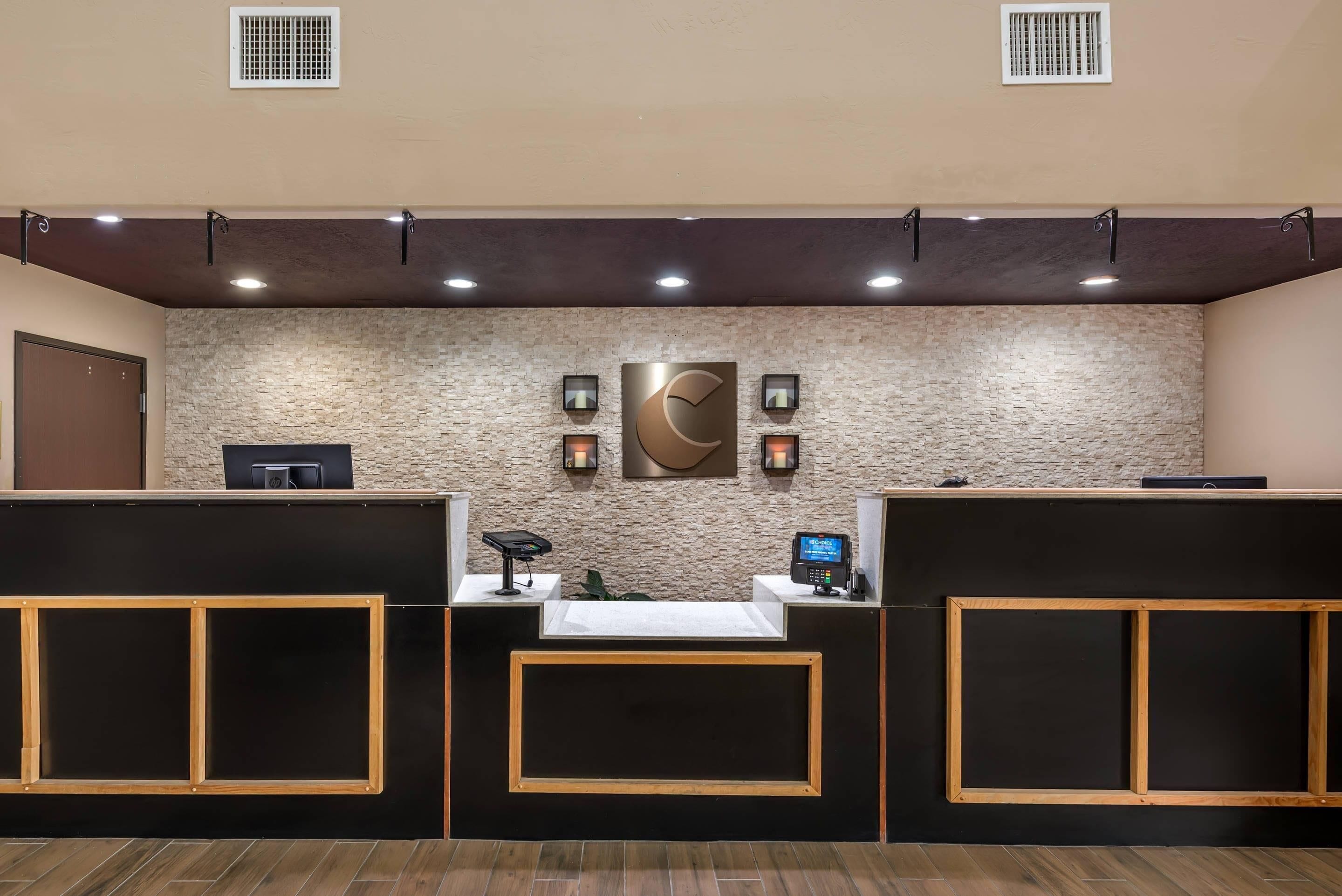 A reception area with a stone wall, a large clock, and two reception desks.