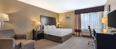 A hotel room with a bed, a desk, a chair, and a TV.