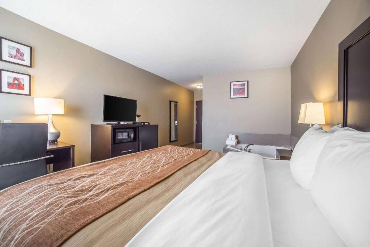 Una habitación de hotel con cama, escritorio, televisión y baño.