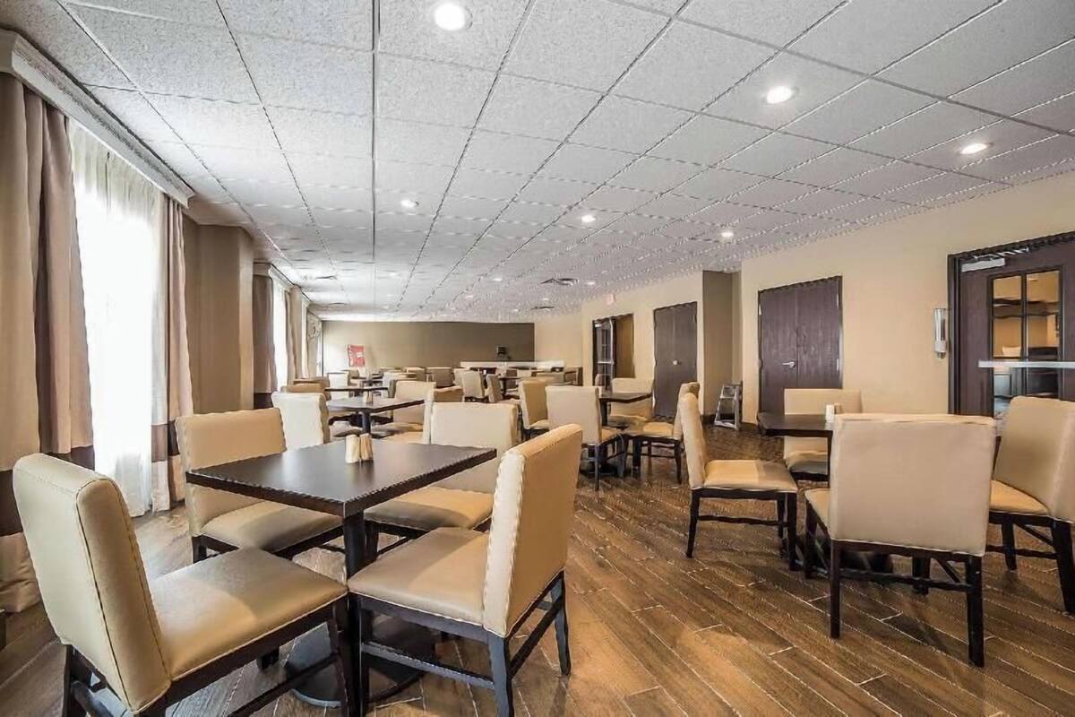 Un comedor de hotel con varias mesas y sillas, techo de azulejos y suelo de madera.