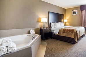 A hotel room with a large bathtub, a neatly made bed with white linens, and a nightstand with a lamp. - Comfort Inn & Suites Vernal - National Monument Area (Vernal)