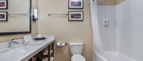 A modern bathroom with a white sink, toilet, and bathtub. There are two framed pictures on the wall, a towel rack, and a hand dryer.