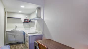 Una kitchenette compacta con microondas, pileta y alacenas.