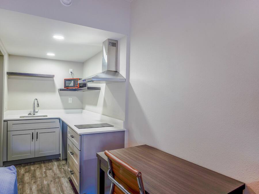 Una kitchenette compacta con microondas, pileta y alacenas.