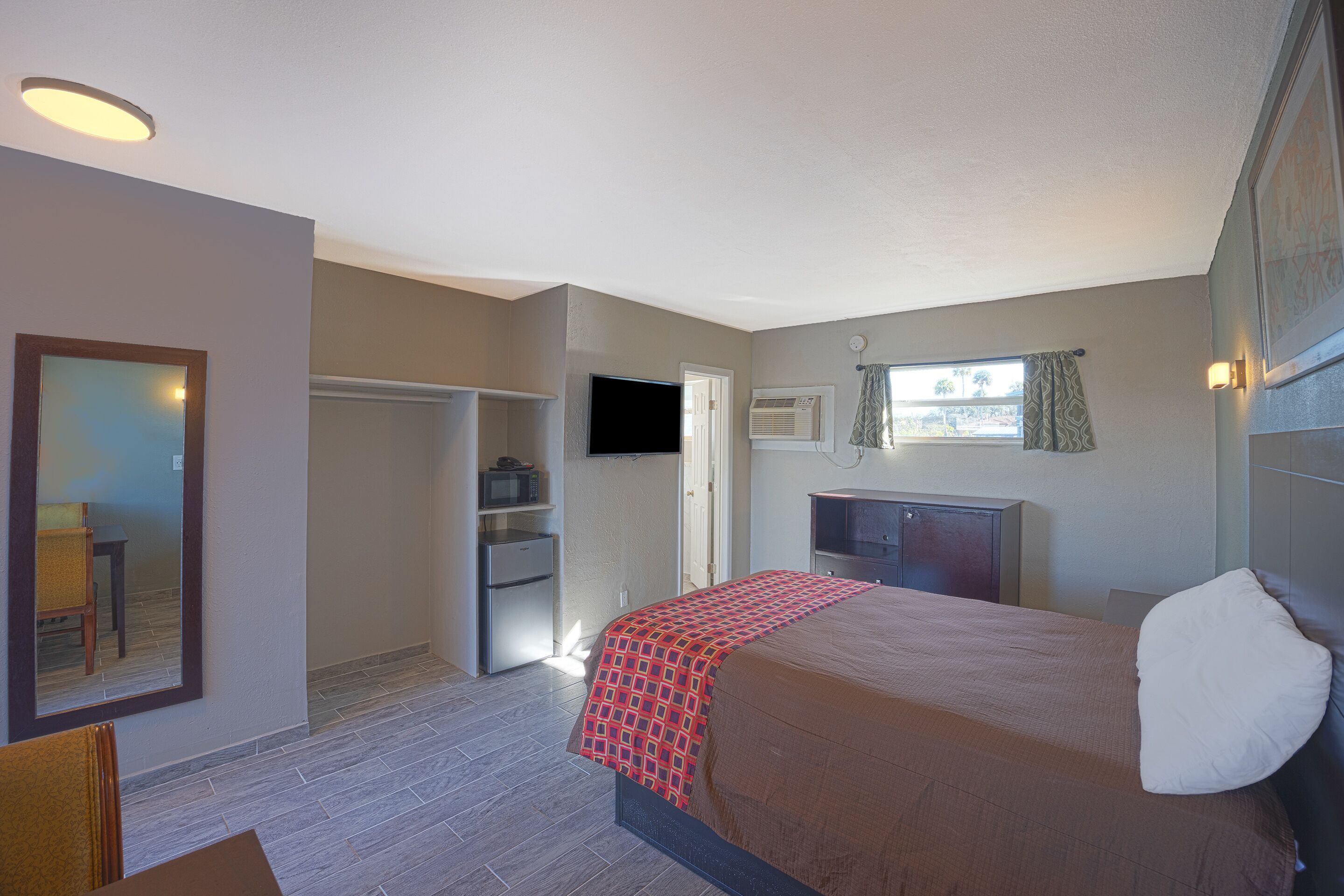 A hotel room with a bed, a TV, a desk, and a wardrobe.