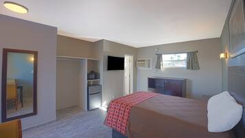 A hotel room with a bed, a TV, a desk, and a wardrobe.
