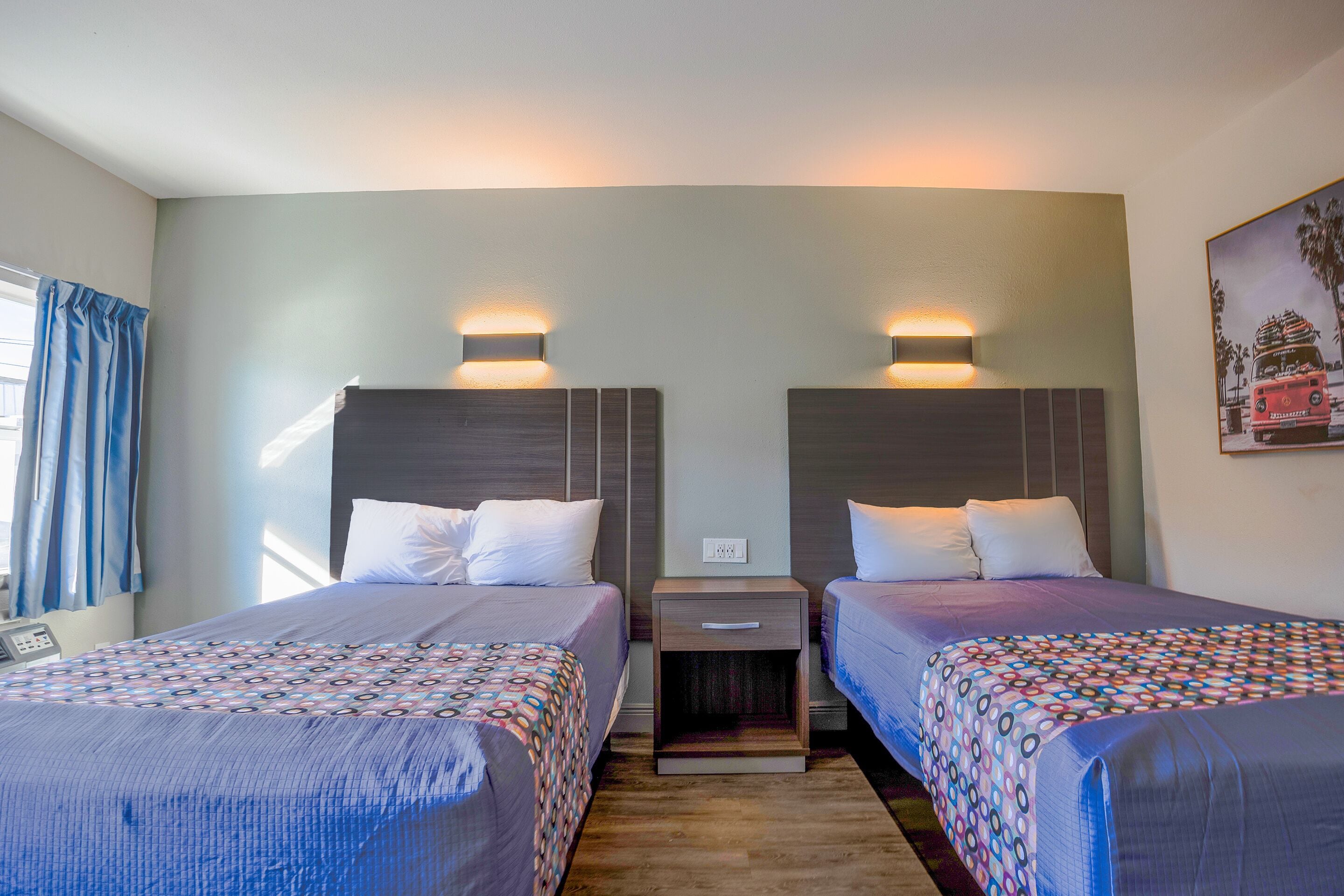Une chambre d’hôtel avec deux lits, chacun doté d’une tête de lit, de tables de chevet et d’un luminaire fixé au mur.