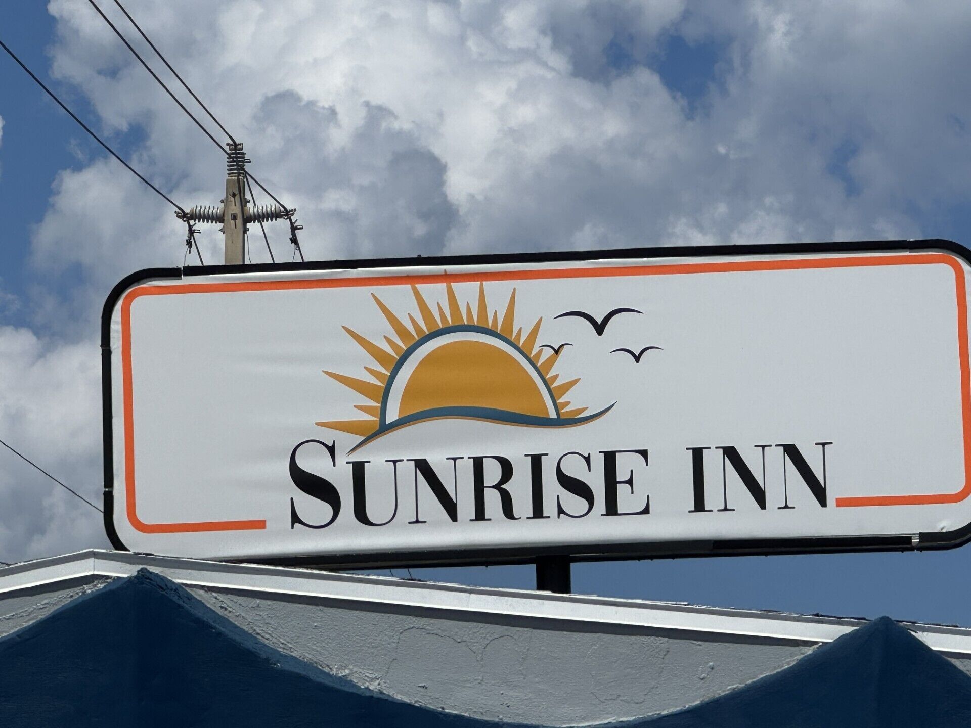 Señal para Sunrise Inn, con un gráfico de sol y pájaros.