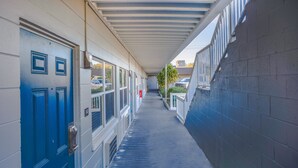 Un couloir avec une porte bleue, des fenêtres et une galerie couverte.