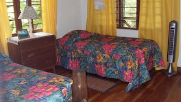 Una habitación con dos camas, un aparador de madera, una lámpara de noche y un calefactor.