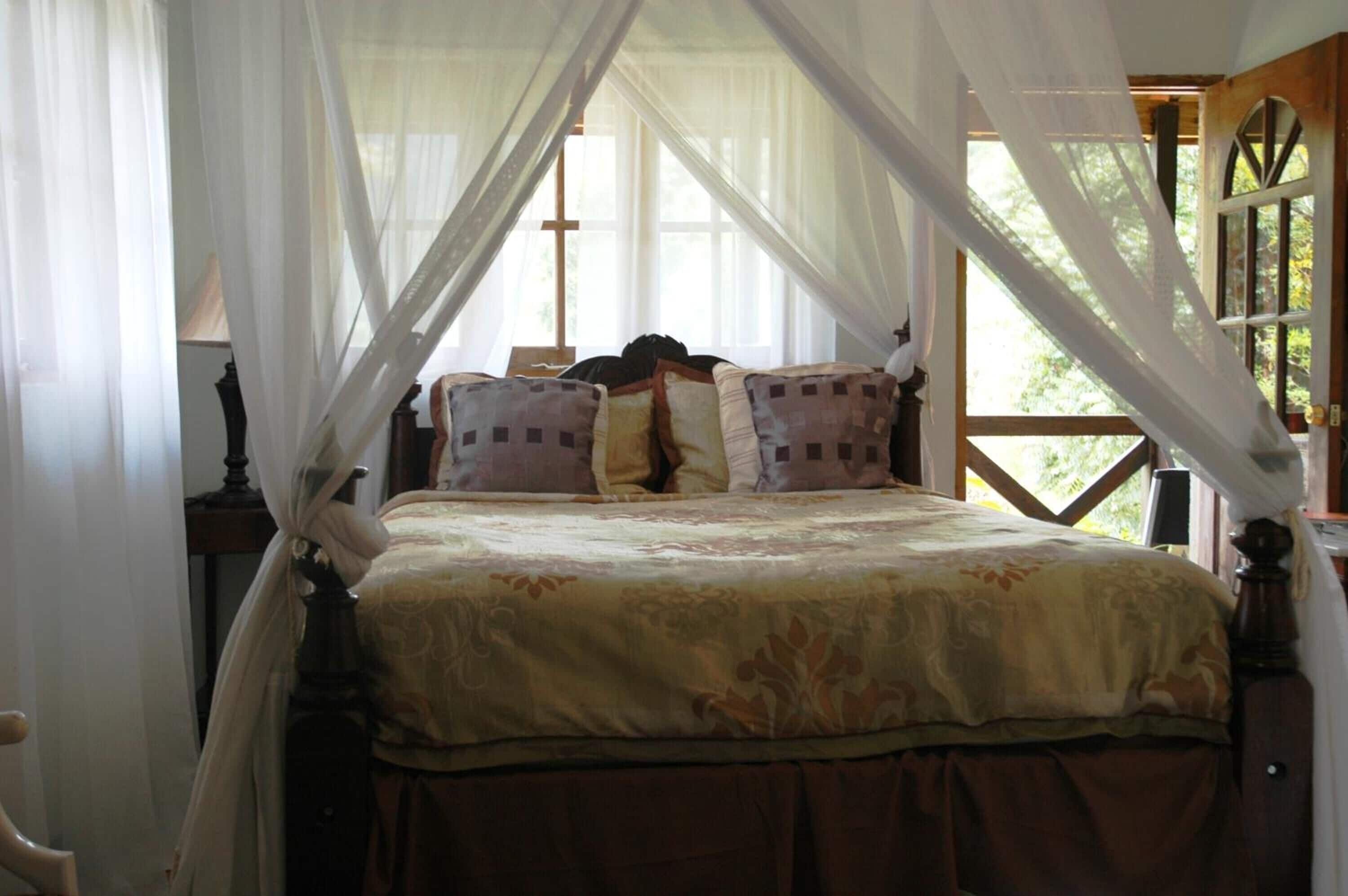 A bed with a canopy, a wooden headboard, and a window with curtains.