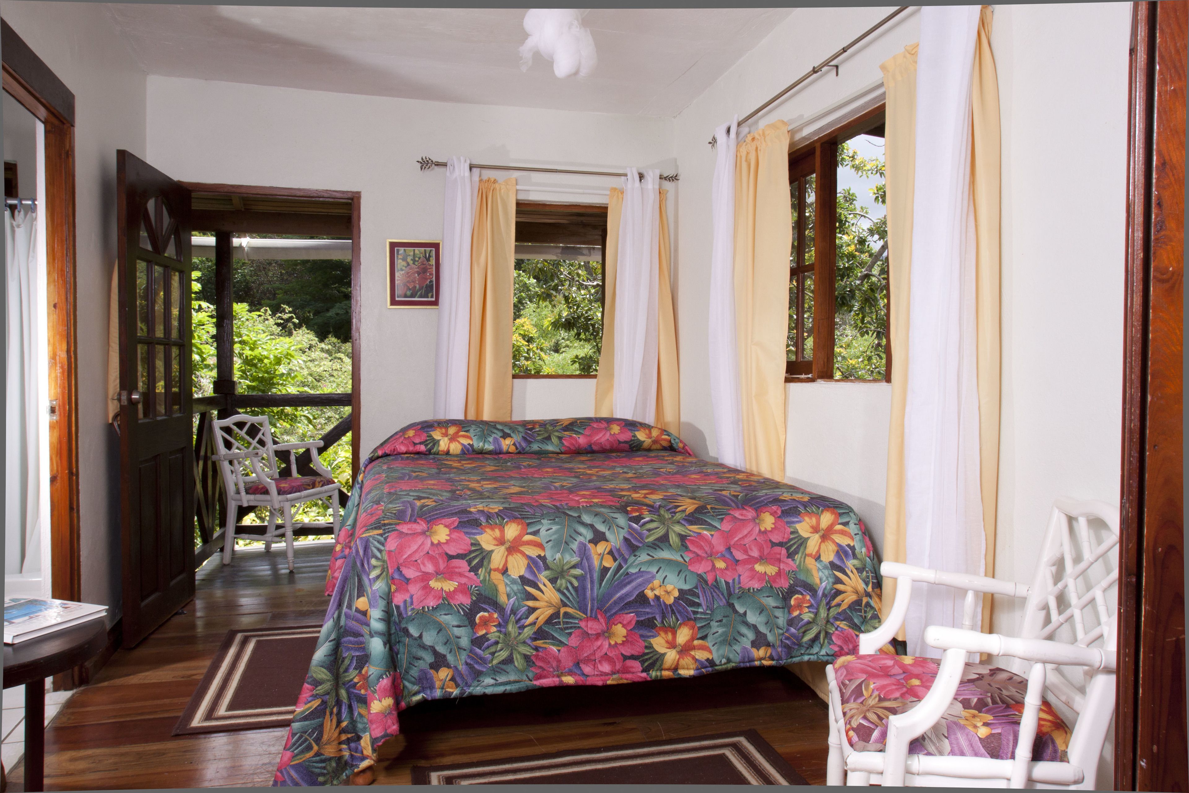 Quarto com uma cama, uma cadeira e uma janela com cortinas.
