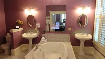 Un baño con dos lavamanos, una bañera y un espejo grande.
