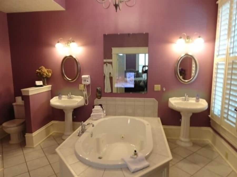 Une salle de bain avec deux lavabos, une baignoire et un grand miroir.