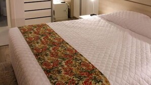 Un dormitorio con una cama grande, cabecera de madera, lámpara de noche y armario con puertas correderas.