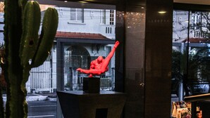 Un vestíbulo con un cactus, un tapete de cuero de vaca, una escultura y vistas a la calle.