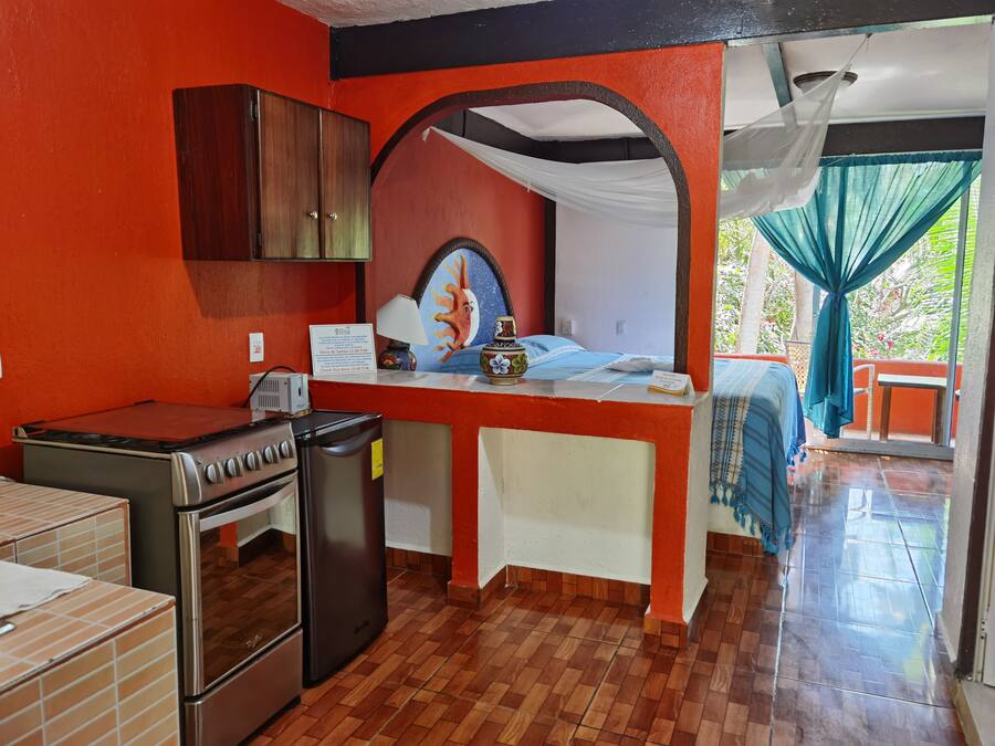 Una cocina compacta con estufa, refrigerador y una pequeña mesa de comedor.