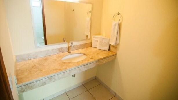 A bathroom with a sink, mirror, and towel rack.