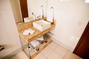 A bathroom with a marble vanity, two sinks, a large mirror, and a towel rack. - Real Palace Hotel (Tres Lagoas)